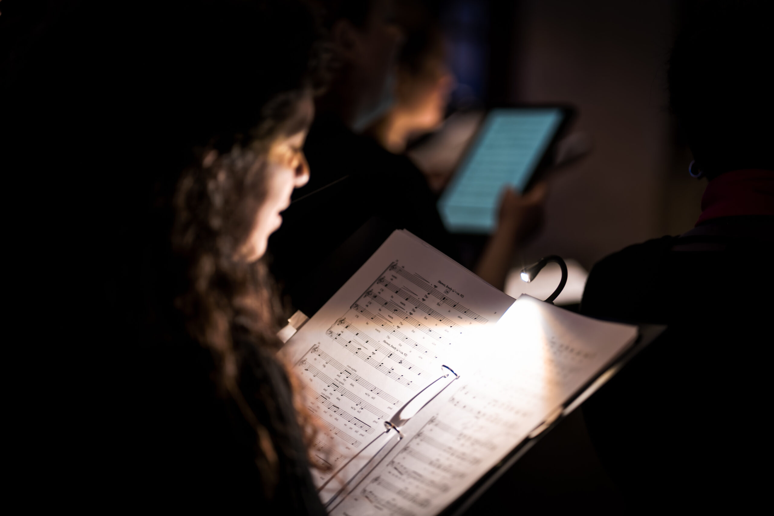 Chanteuse au concert de Noël de nuit regardant sa partition